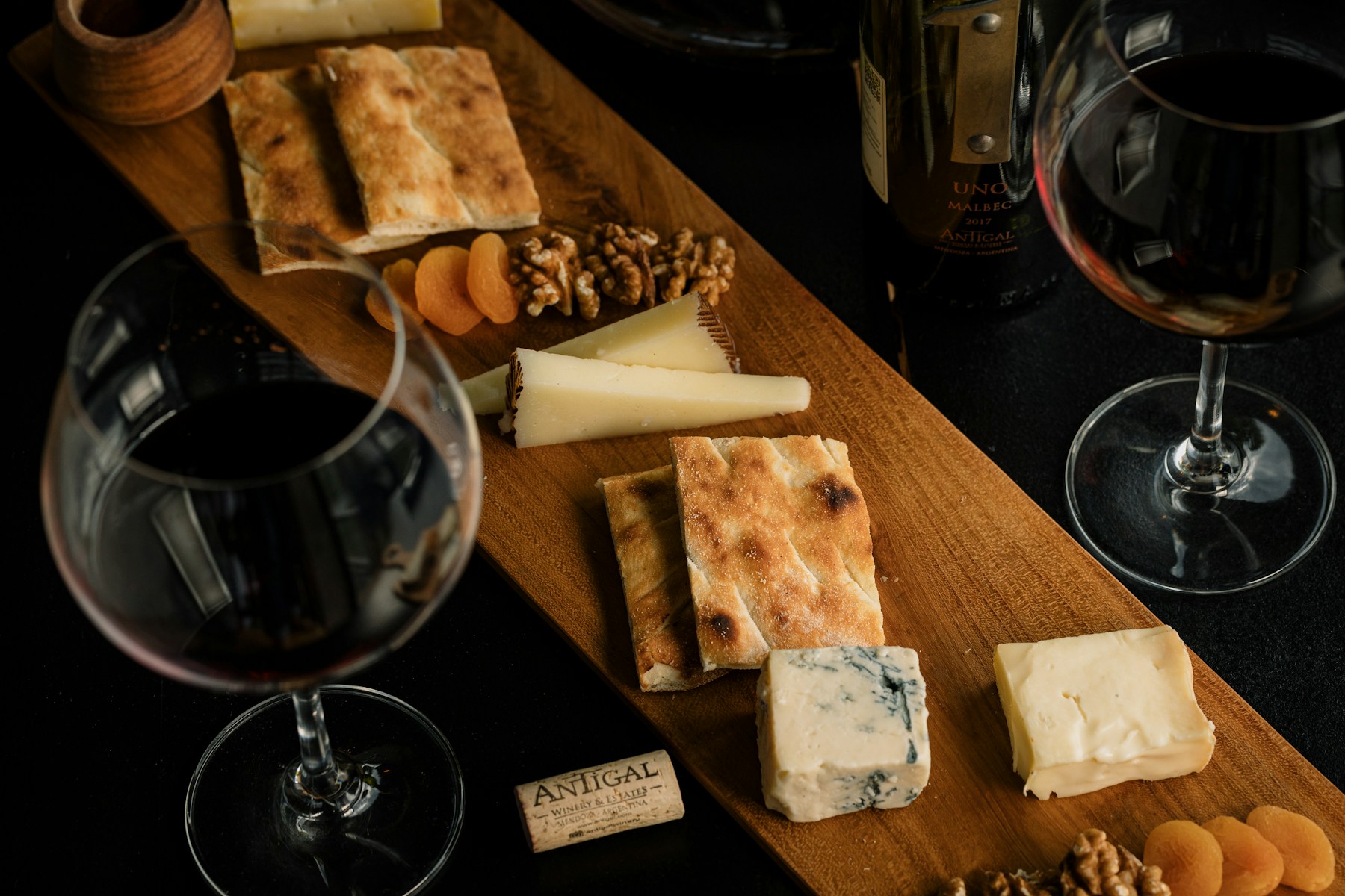 Vinho em garrafa e taças junto de queijos à mesa